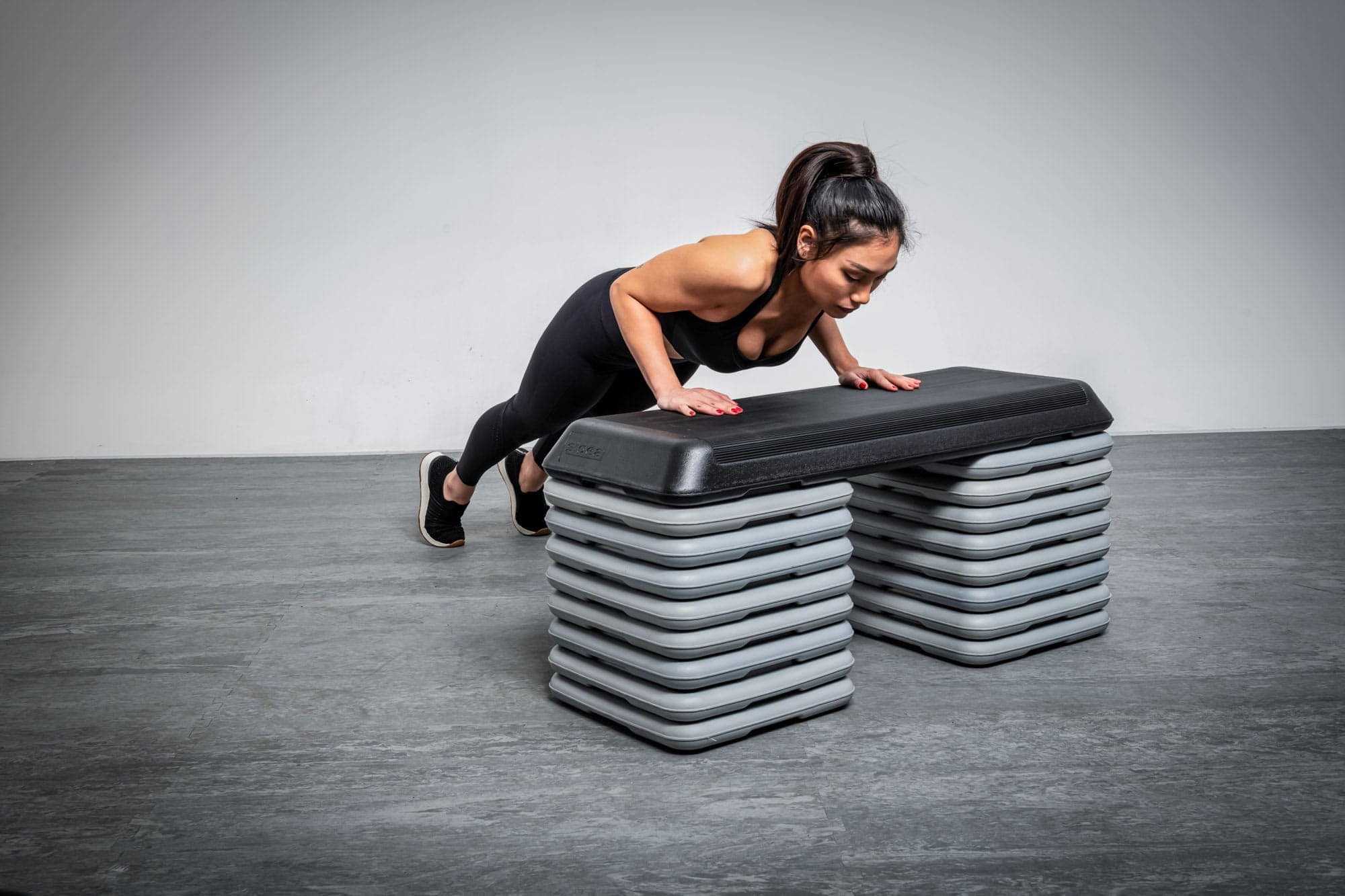 Donna che utilizza uno step aerobico professionale per allenamento cardio in palestra.