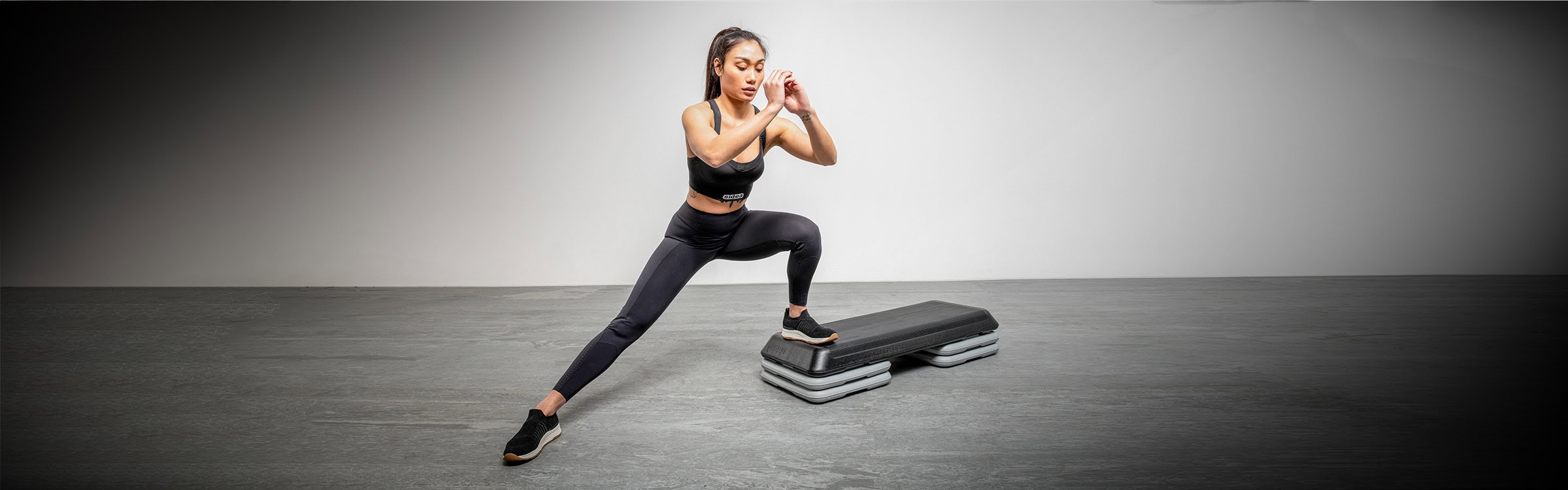 Donna che utilizza attrezzatura fitness professionale Sidea in palestra, esercizio di squat con step.
