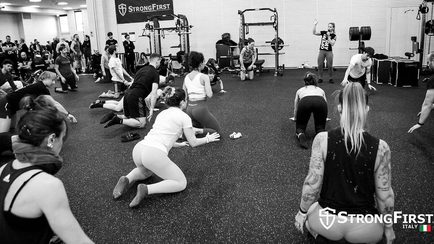 Attrezzatura fitness professionale per allenamenti di gruppo in palestra, con persone che praticano esercizi a terra e in piedi, in un ambiente moderno e ben attrezzato.