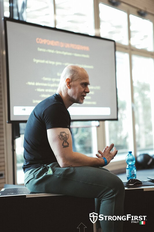 Allenamento fitness professionale con istruttore in aula, seduto e che ascolta attentamente durante una sessione di formazione su attrezzature sportive di alta qualità.