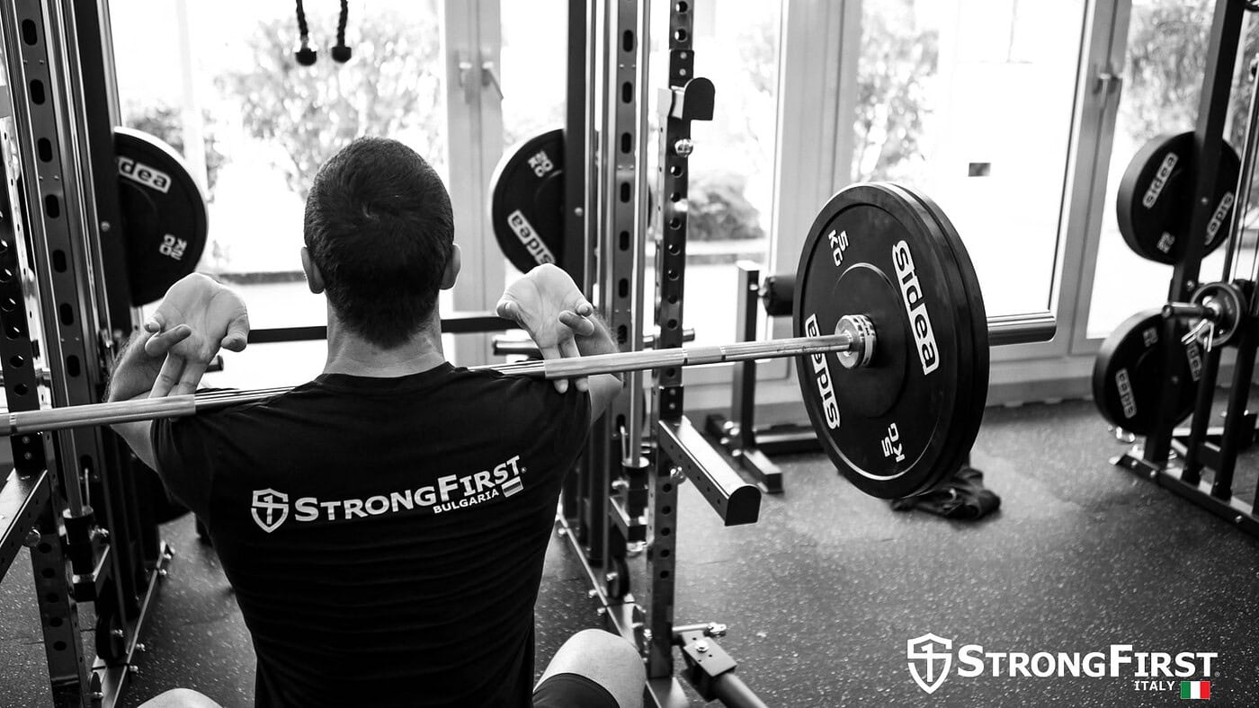 Relatore che presenta in una piattaforma fitness con pubblico, attrezzature professionali per allenamento e dimostrazioni di esercizi.