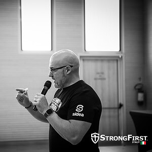 Fitness instructor speaking during a training session, with professional strength and hypertrophy equipment, in a Sidea fitness centre.