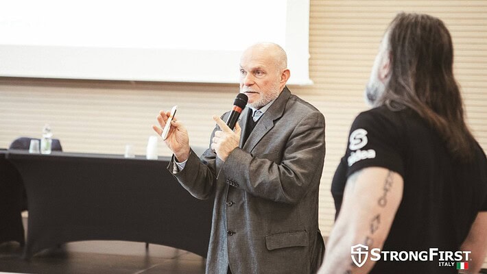 Foto de un ponente presentando en un evento de fitness con público.