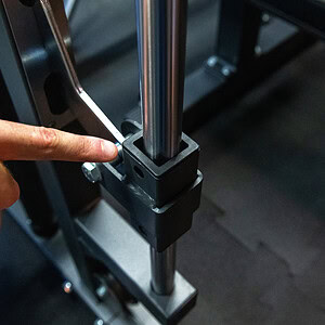 Dettaglio di un supporto in plastica per attrezzature fitness professionali, con una mano che indica la posizione corretta di montaggio.